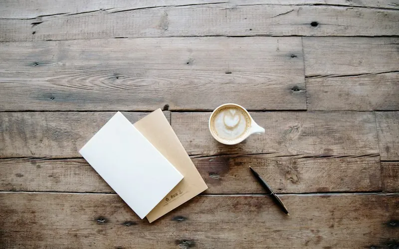 Courrier, stylo et tasse posés sur une table en bois